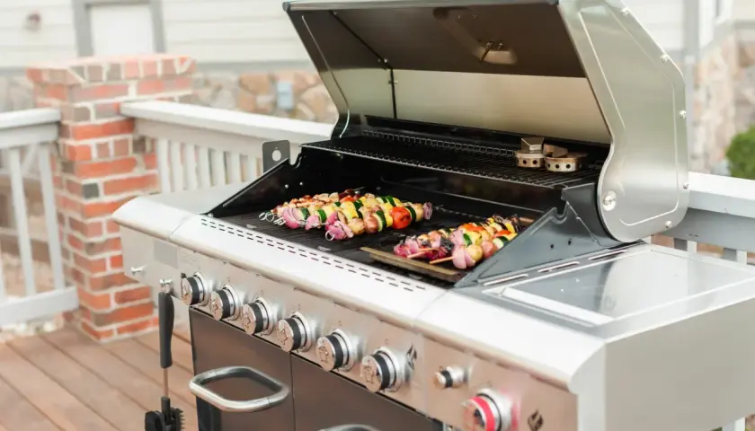 Brochettes colorées en cours de cuisson sur un barbecue à gaz. Les légumes et la viande sont prêts à être dégustés.