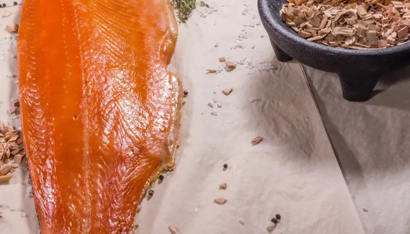 Filet de saumon fumé, sel, poivre et copeaux de bois. Quelle sciure pour fumoir ? Des copeaux de bois pour un fumage parfait.