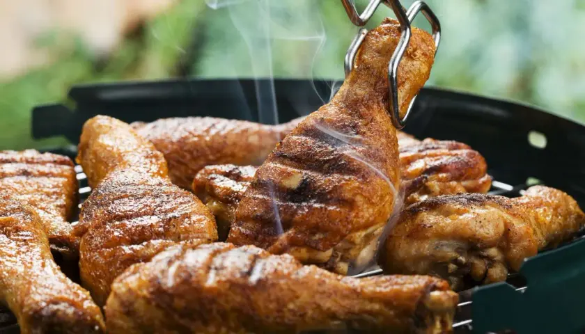 Des pilons de poulet grillés, savamment préparés avec une marinade pilon de poulet barbecue, dégagent une fumée appétissante sur le barbecue.
