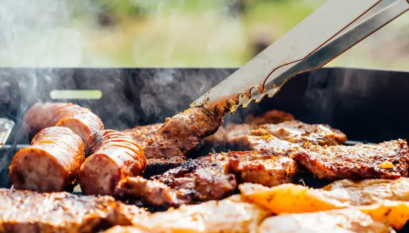 Des saucisses et des morceaux de viande au barbecue, fumants et grillés à la perfection. Un délice estival.