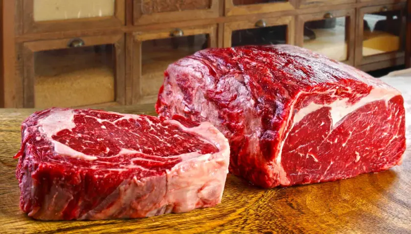 Deux pièces de viande rouge vif, un steak épais et un rôti, sur une planche en bois. Ce filet de bœuf promet un repas savoureux.