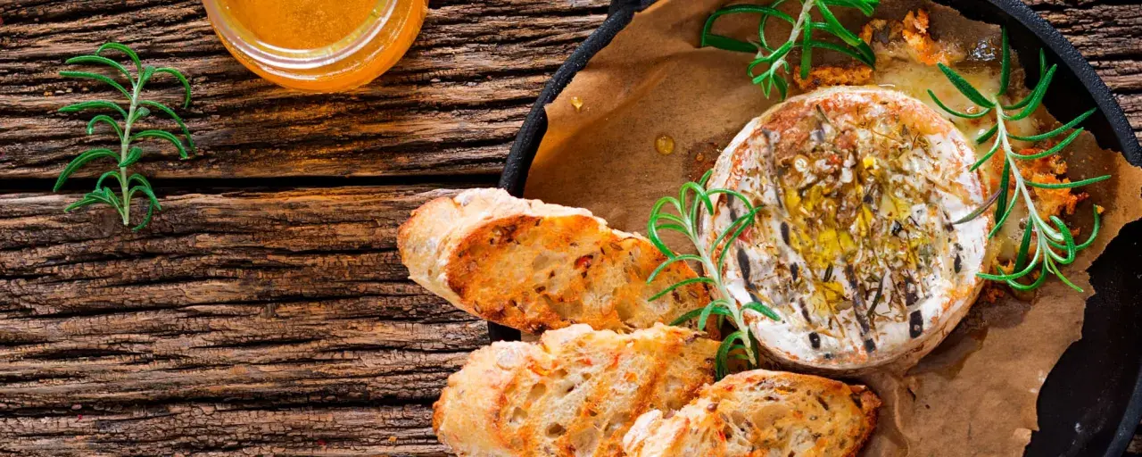 Un délicieux fromage au barbecue, doré et fondant, servi avec du pain grillé et du romarin frais.