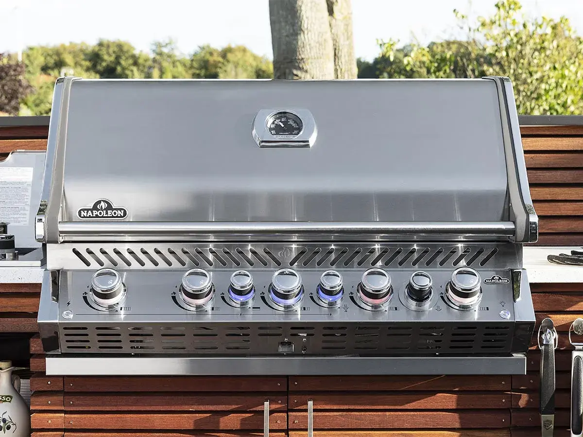 Barbecue à gaz Napoleon avec couvercle fermé, prêt pour de nouvelles recettes. Ses boutons lumineux indiquent la température parfaite.