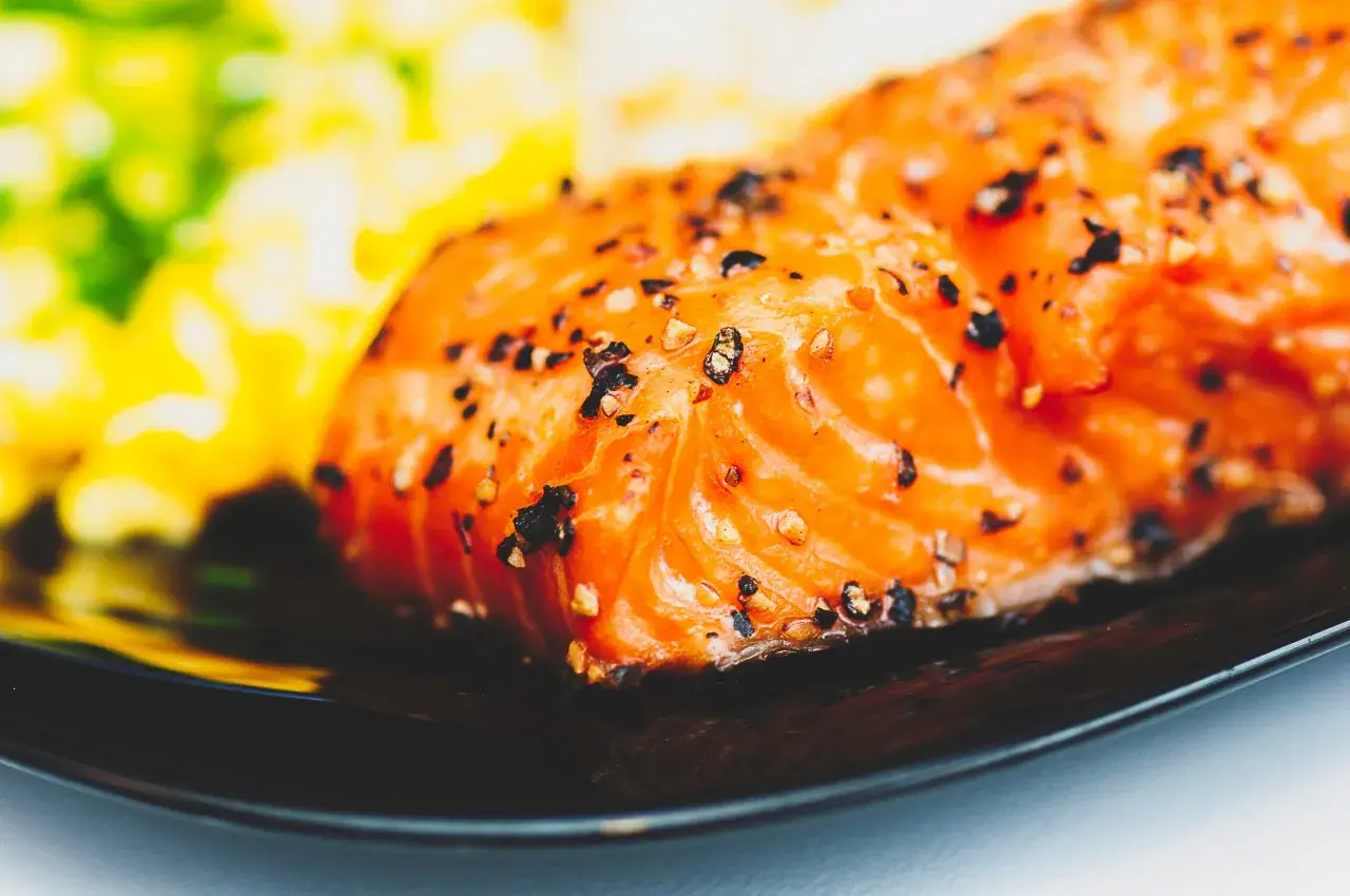 Un délicieux filet de saumon, assaisonné de poivre, prêt pour un barbecue de la mer. Accompagné d'une purée verte et jaune floue.