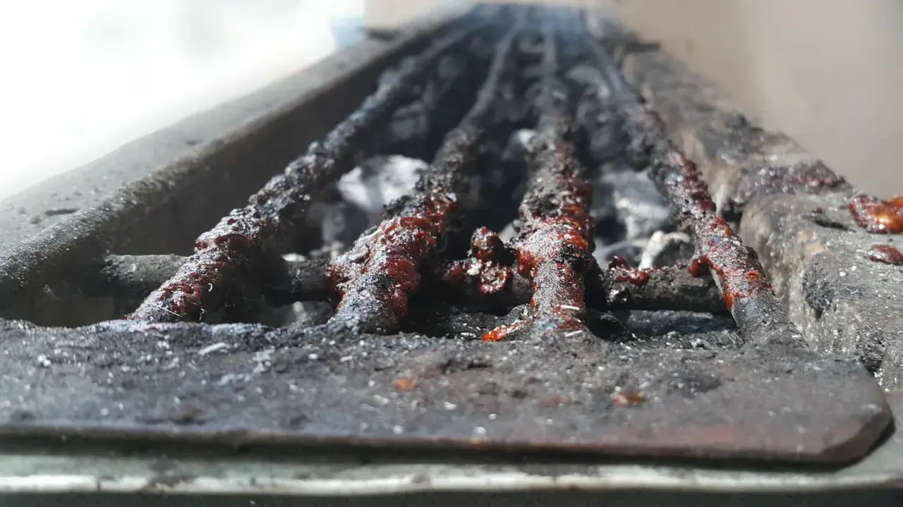 Grille de barbecue à charbon très sale, couverte de résidus de cuisson. Il est temps de nettoyer ce barbecue charbon pour la prochaine utilisation.