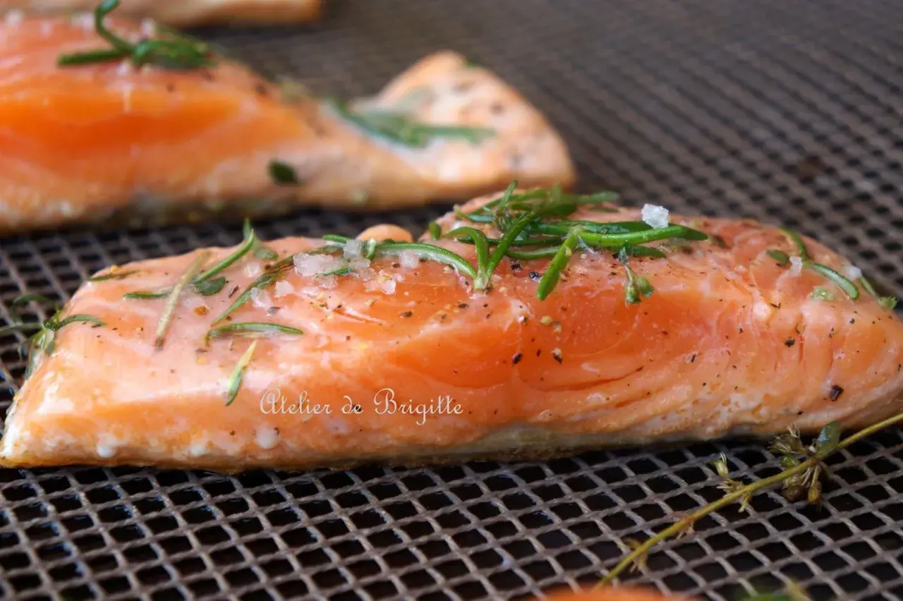 Filets de saumon sur une grille, assaisonnés de sel, poivre et romarin. Parfait pour une cuisson plancha à la bonne température.