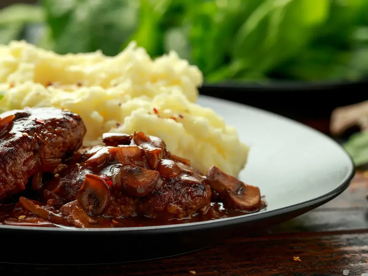 Délicieuses joues de bœuf mijotées dans une sauce aux champignons, servies avec une purée de pommes de terre onctueuse.