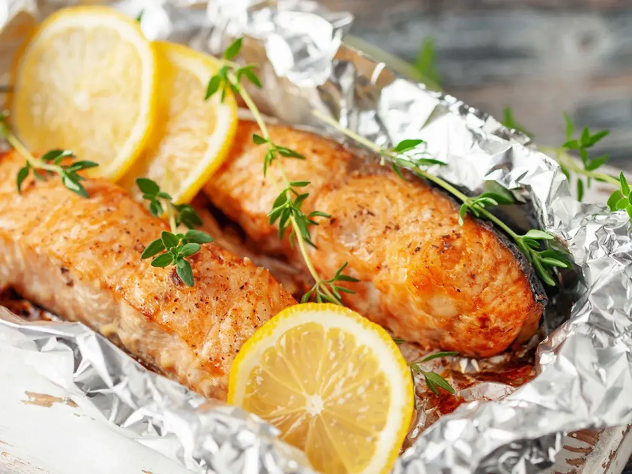 Deux pavés de poisson, cuits en papillote sur la plancha, ornés de rondelles de citron et de brins de thym frais.
