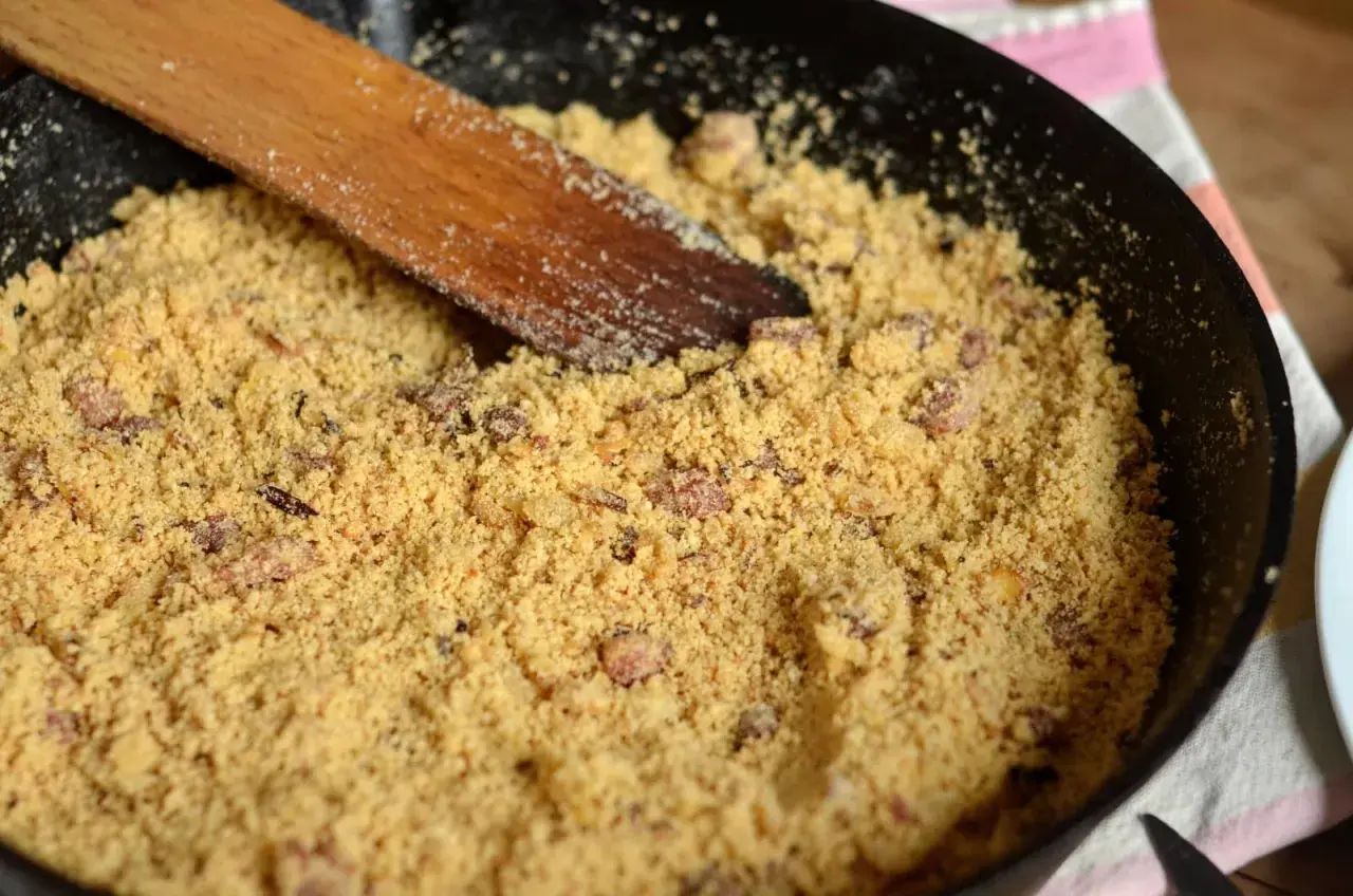 Préparation d'une recette de farine de maïs dans une poêle avec une spatule en bois.