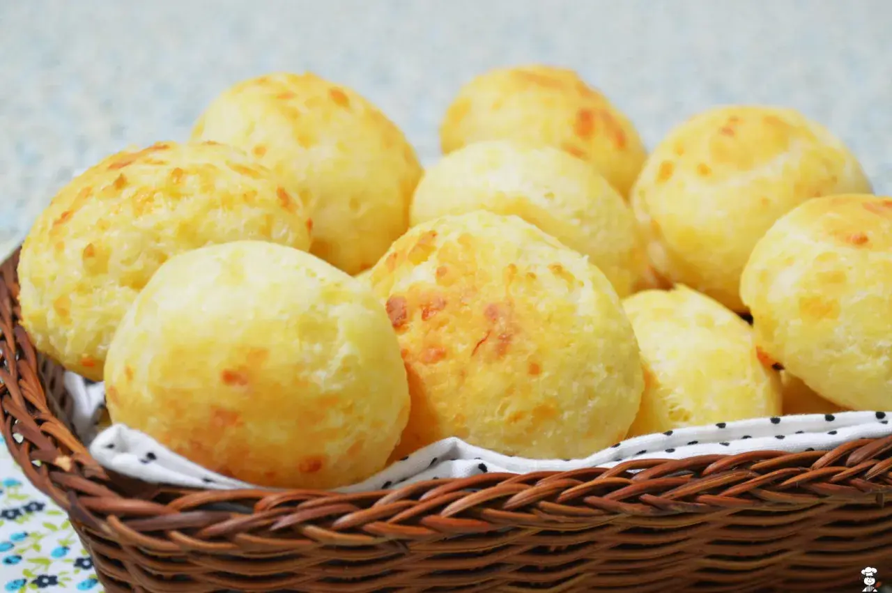 Un panier en osier déborde de délicieux pao de queijo dorés, parfaits pour un goûter.