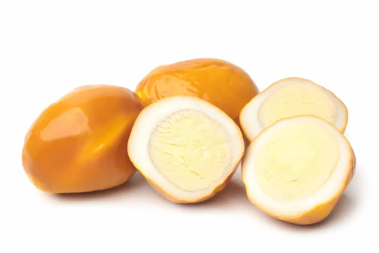 Œufs fumés entiers et coupés en deux, révélant un jaune d'œuf crémeux.