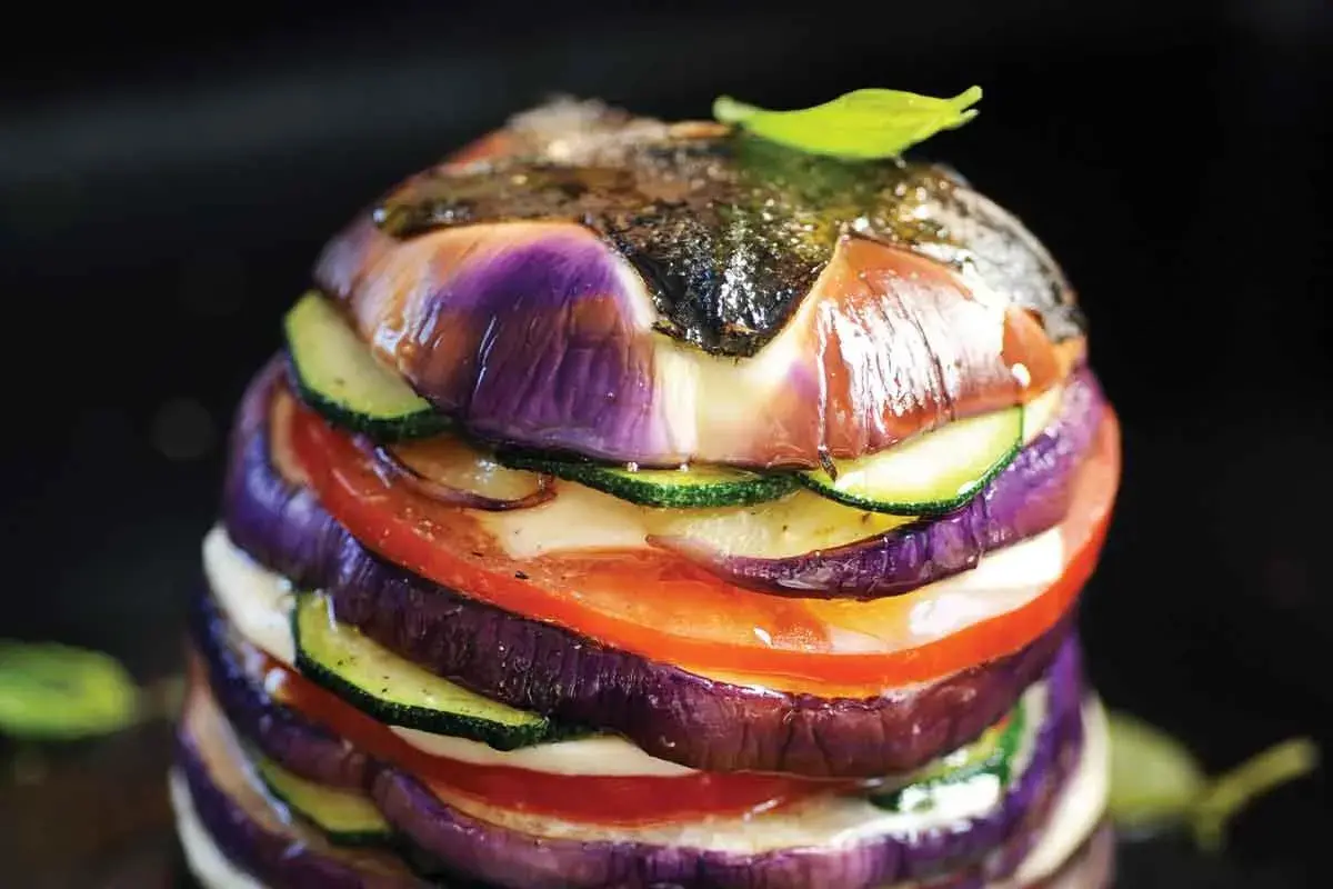 Délicieux légumes à la plancha, un empilement coloré d'aubergines, courgettes et tomates, avec une touche de pomme de terre cachée.