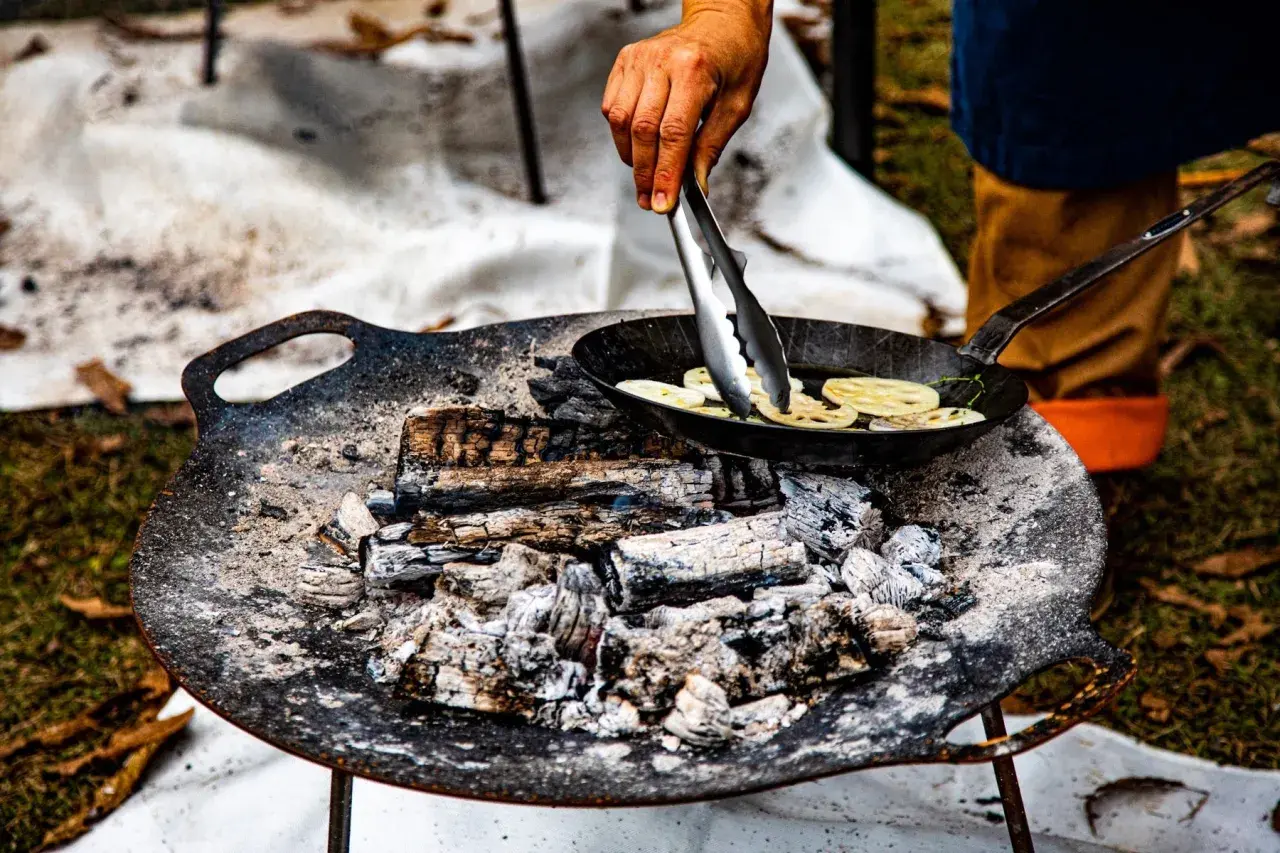 Cuisson de rondelles de lotus dans une poêle sur un feu de bois. La température du barbecue est parfaite pour cette cuisson.