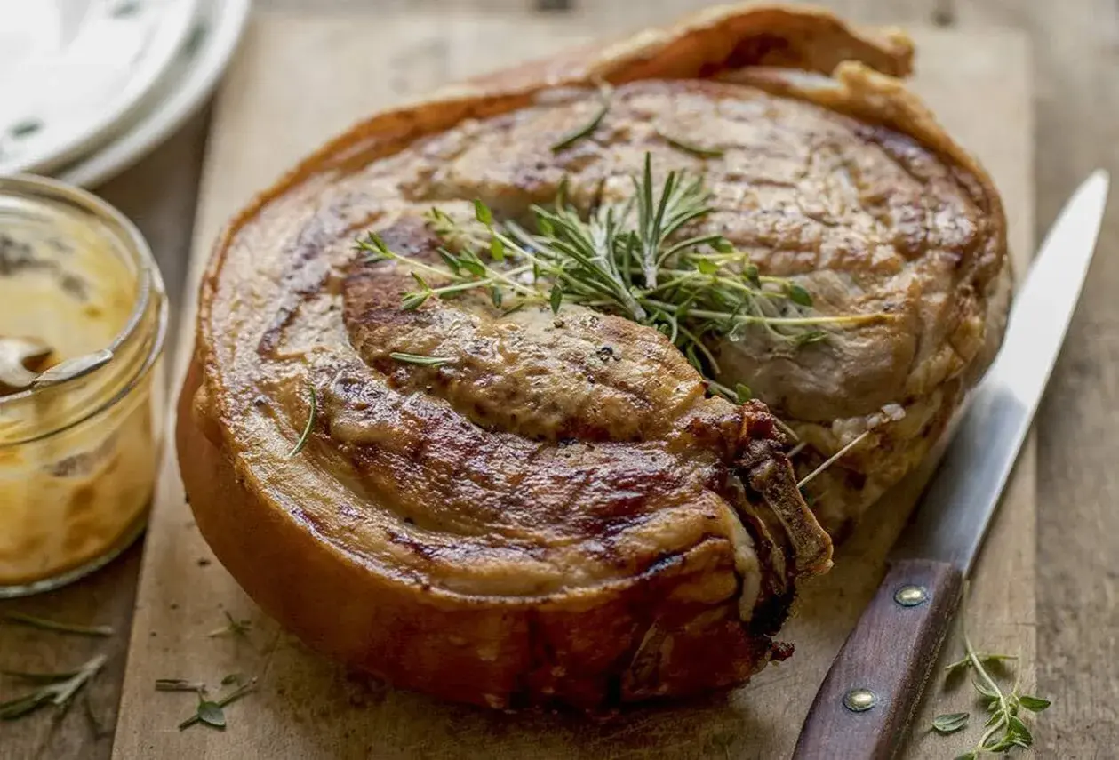 Rouelle de porc au barbecue, dorée et savoureuse, garnie de romarin et de thym. Un délice à partager !