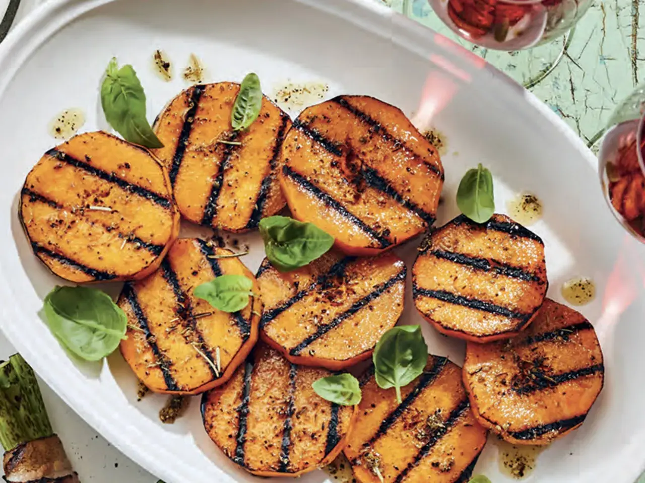 Tranches de courge au barbecue, grillées et assaisonnées, garnies de feuilles de basilic frais. Un délice estival !