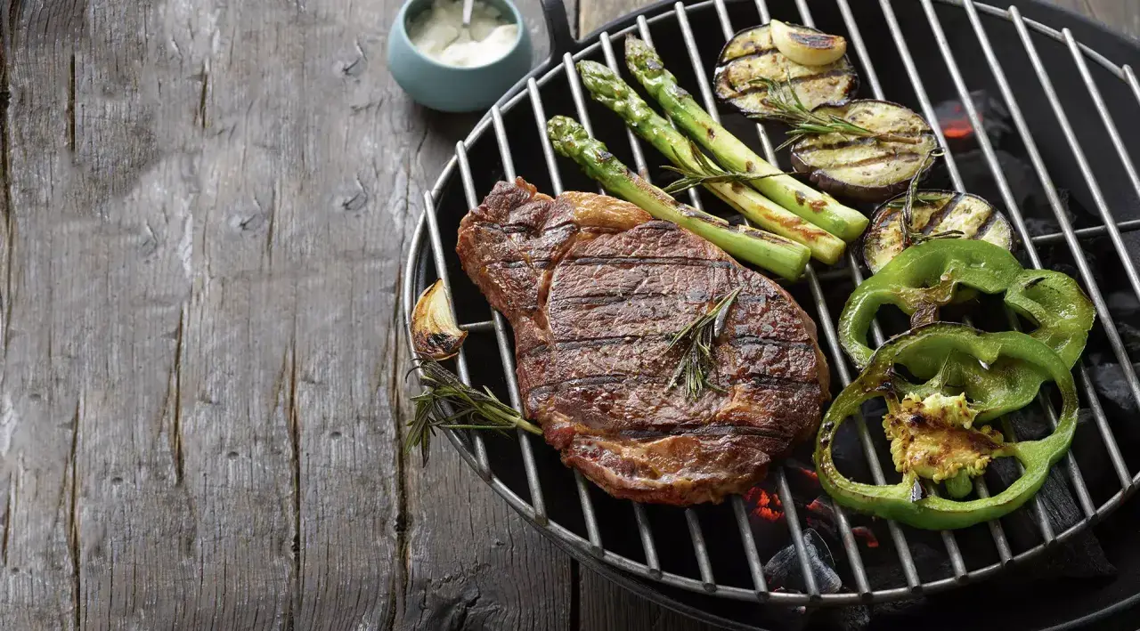 Un steak savoureux, des asperges, des aubergines et des poivrons verts sur un barbecue. Parfait pour savoir que faire cuire au barbecue.