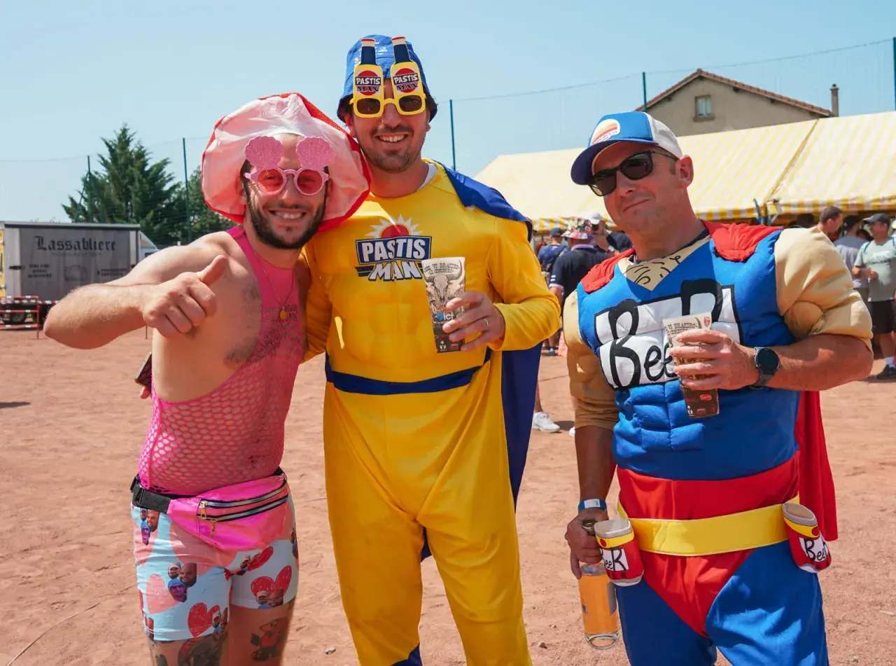 Trois amis costumés pour une soiree brasero, l'un en rose flashy, l'autre en "Pastis Man" jaune, et le dernier en super-héros "Beer".