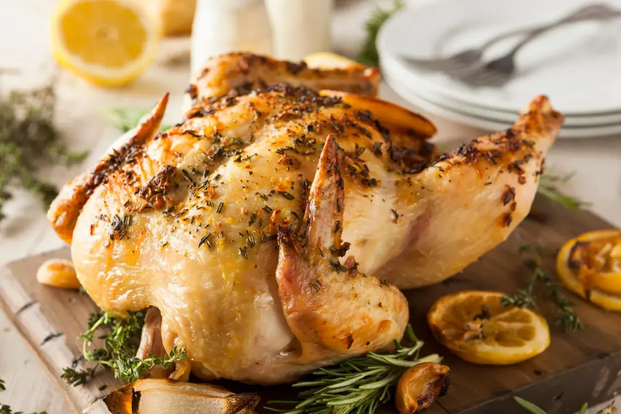 Un poulet entier au barbecue, doré et savoureux, garni d'herbes et de quartiers de citron grillés. Un délice pour les papilles !