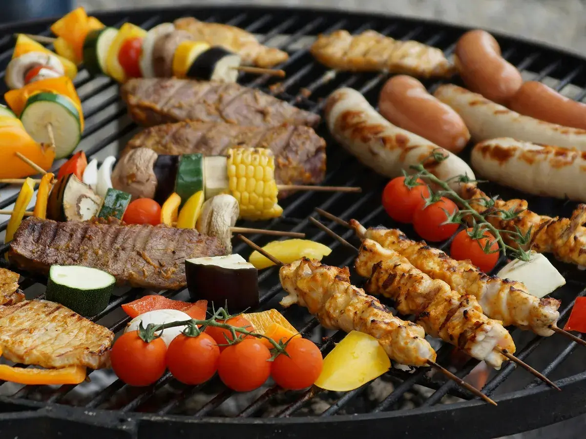 Brochettes de poulet, saucisses, steaks et légumes sur un barbecue. La température parfaite pour un barbecue savoureux.