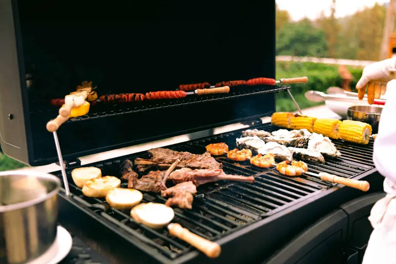 Viande, crevettes, huîtres et maïs sur un barbecue à gaz. Le fumage barbecue gaz ajoute une saveur délicieuse.