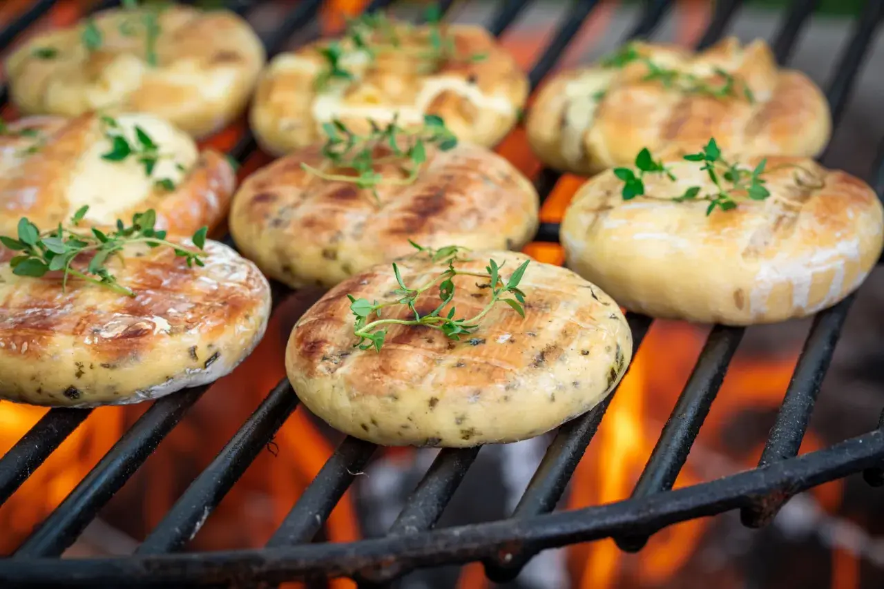 Ronds de halloumi au barbecue, dorés et parsemés de thym frais, grésillant sur les braises ardentes.