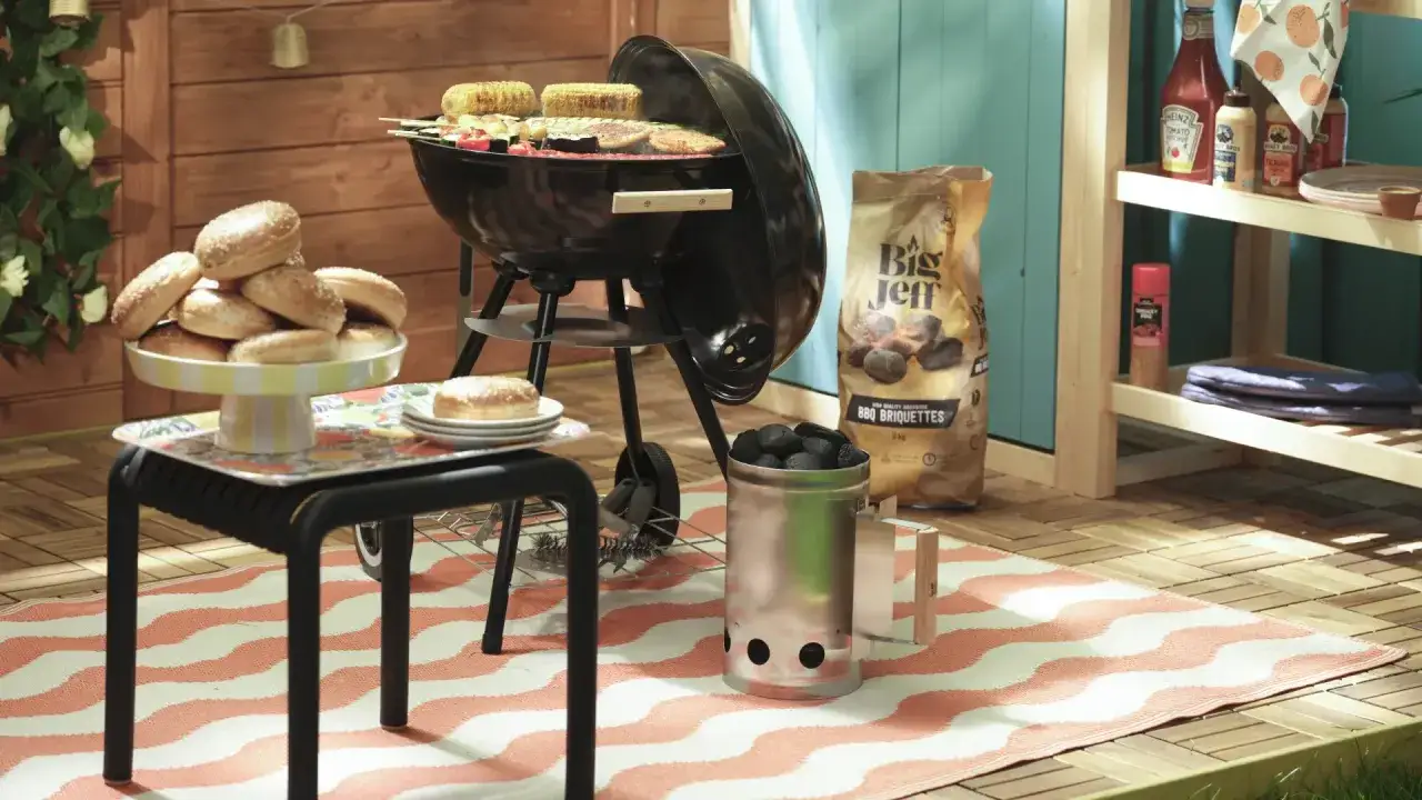 Préparation d'une soiree barbecue party : grill prêt, pains à burger empilés, charbon et condiments à portée de main.