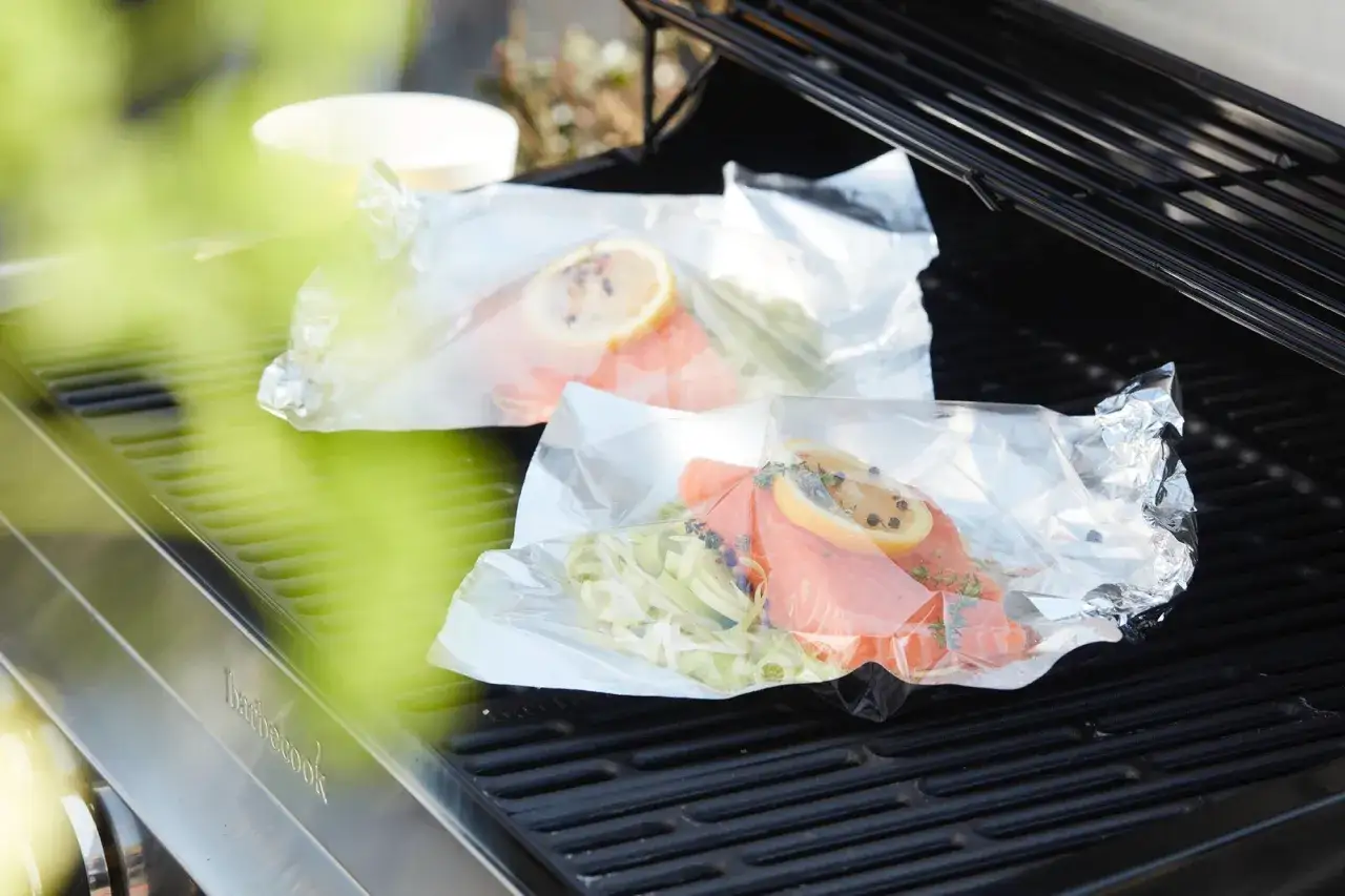 Deux papillotes de poisson barbecue, saumon, citron et herbes, prêtes à cuire sur le grill.