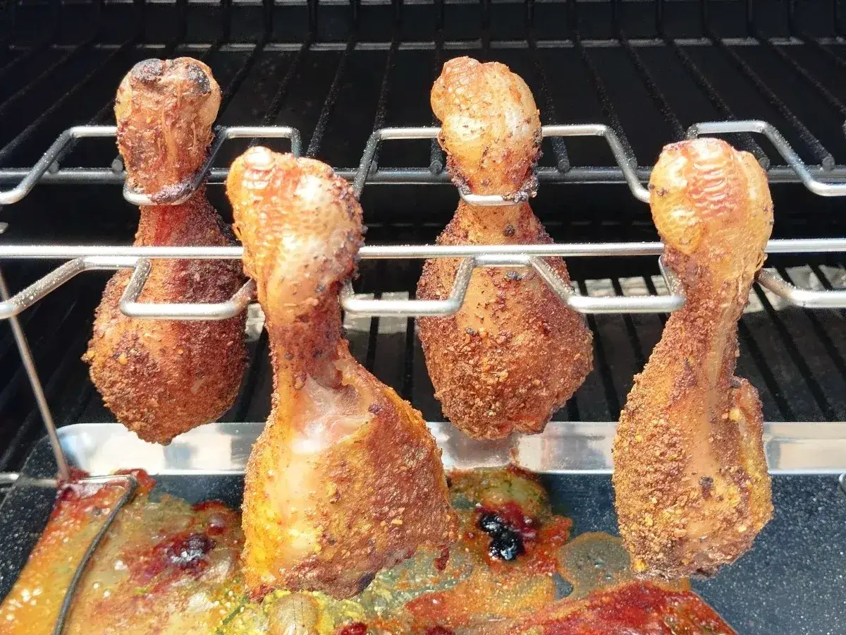 Pilon de poulet en marinade barbecue, grillés à la perfection sur un support. La peau est dorée et croustillante, prête à être dégustée.