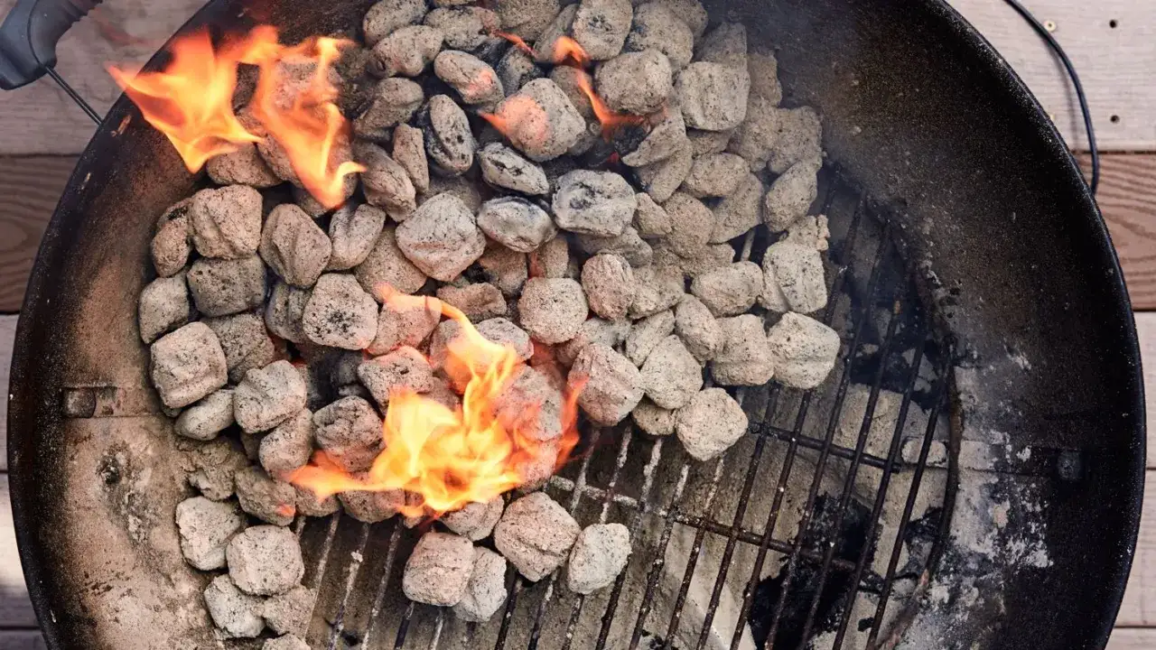 Braises de charbon s'allument dans un barbecue, prêtes pour une cuisson indirecte savoureuse.