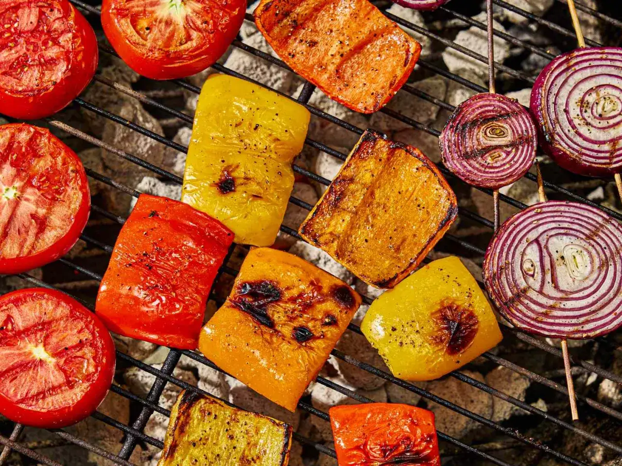 Tomates, poivrons et oignons grillés sur un barbecue à gaz. Le temps de cuisson barbecue gaz est parfait pour ces légumes colorés.