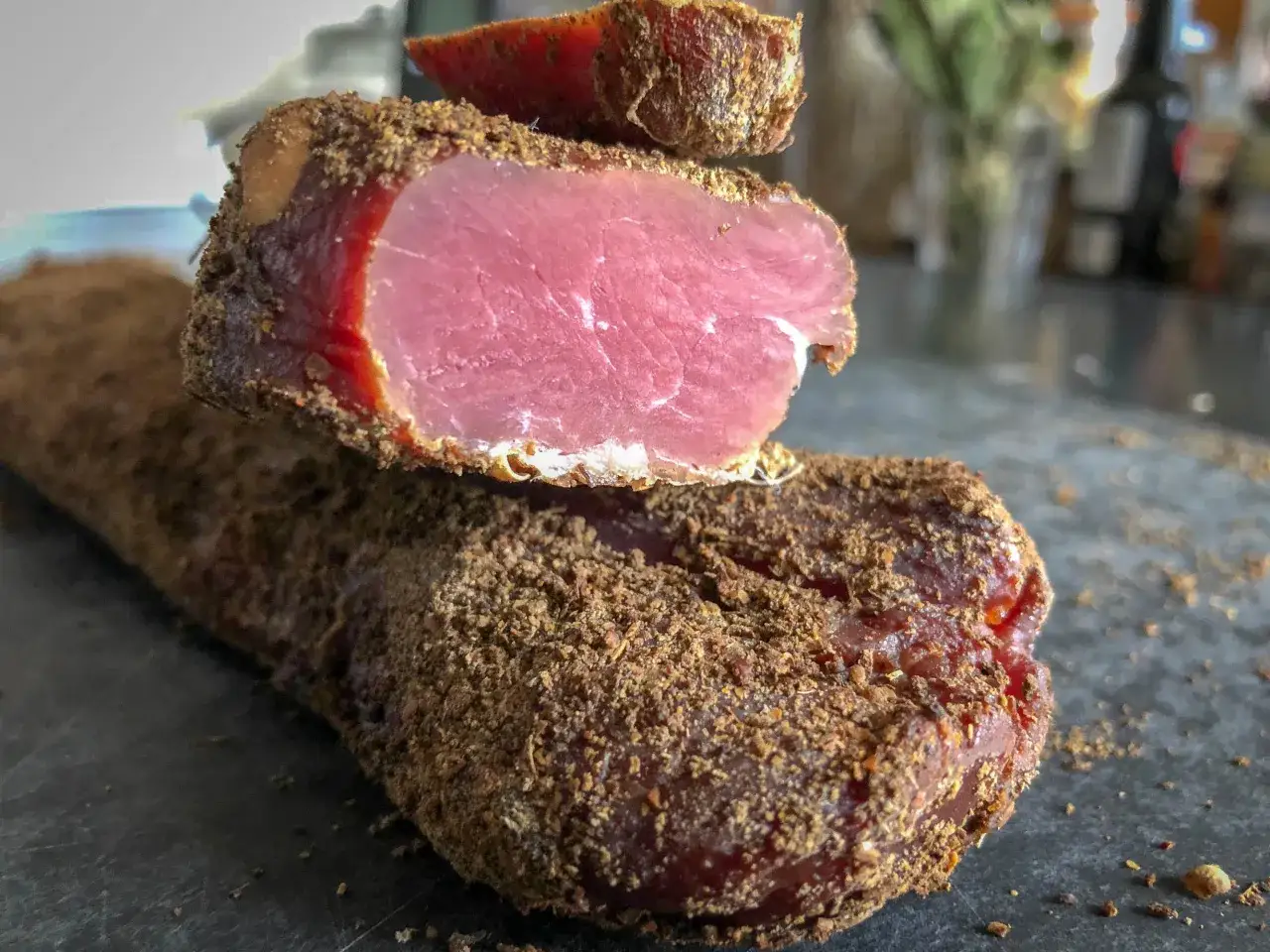 Filet mignon enrobé d'épices, prêt pour le temps de salage avant fumage. La viande rose vif contraste avec la croûte brune.