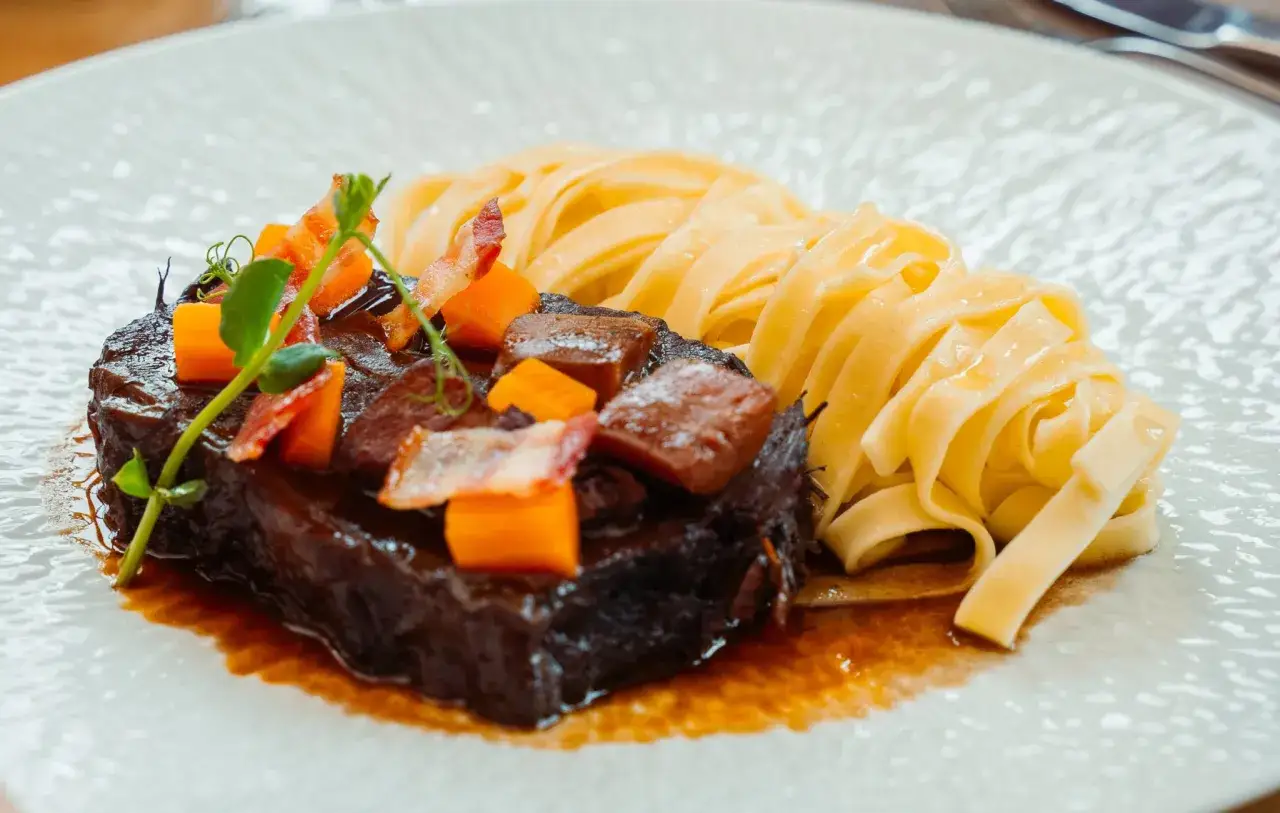 Un g&eacute;n&eacute;reux paleron de boeuf brais&eacute;, garni de d&eacute;s de carottes et de lardons, servi avec des tagliatelles fra&icirc;ches.