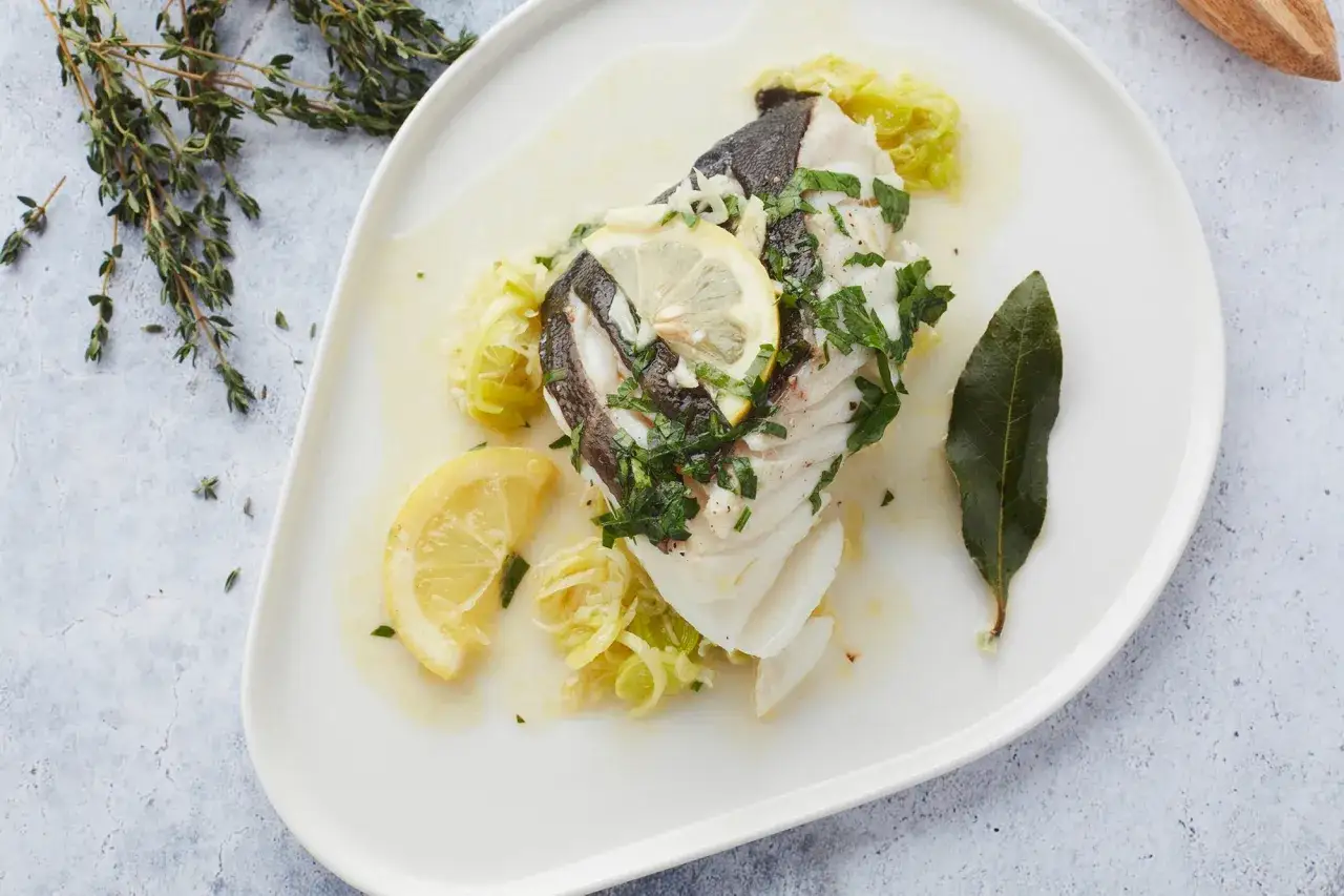 Délicieux cabillaud au barbecue, servi avec des poireaux fondants, des rondelles de citron et des herbes fraîches. Un plat léger et savoureux.