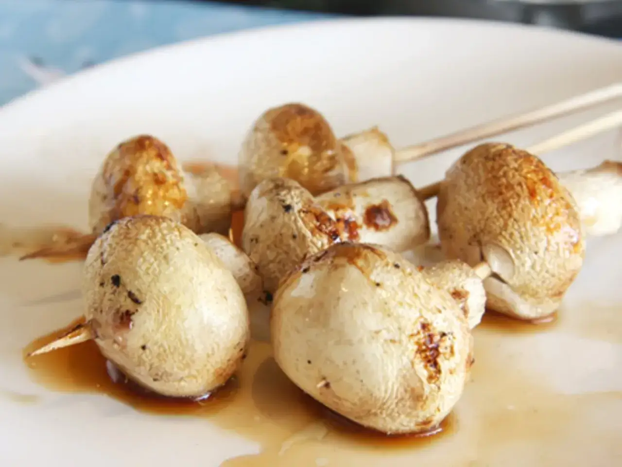 Champignons au barbecue, dorés et juteux, sur une assiette blanche, prêts à être dégustés.