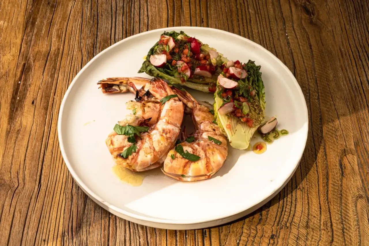 Gambas barbecue grillées, servies avec des quartiers de laitue romaine garnie d'une salsa fraîche et d'herbes.