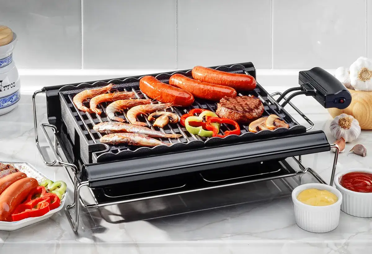 Un barbecue de table électrique avec crevettes, saucisses, steak, poivrons et champignons.