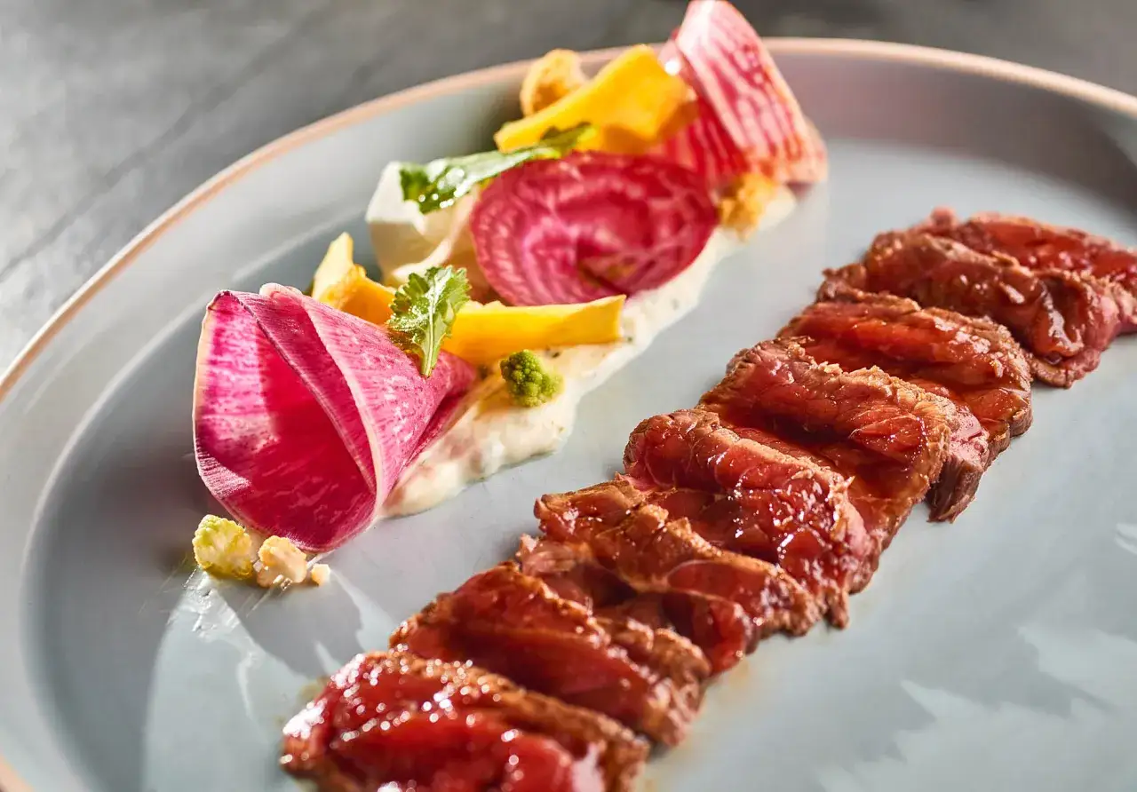 Délicieux tataki de boeuf, servi avec des légumes croquants et une sauce crémeuse.