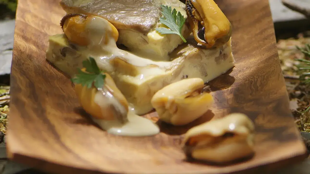 Un délice de moules poulette, nappées d'une sauce onctueuse, servies sur un plat en bois.