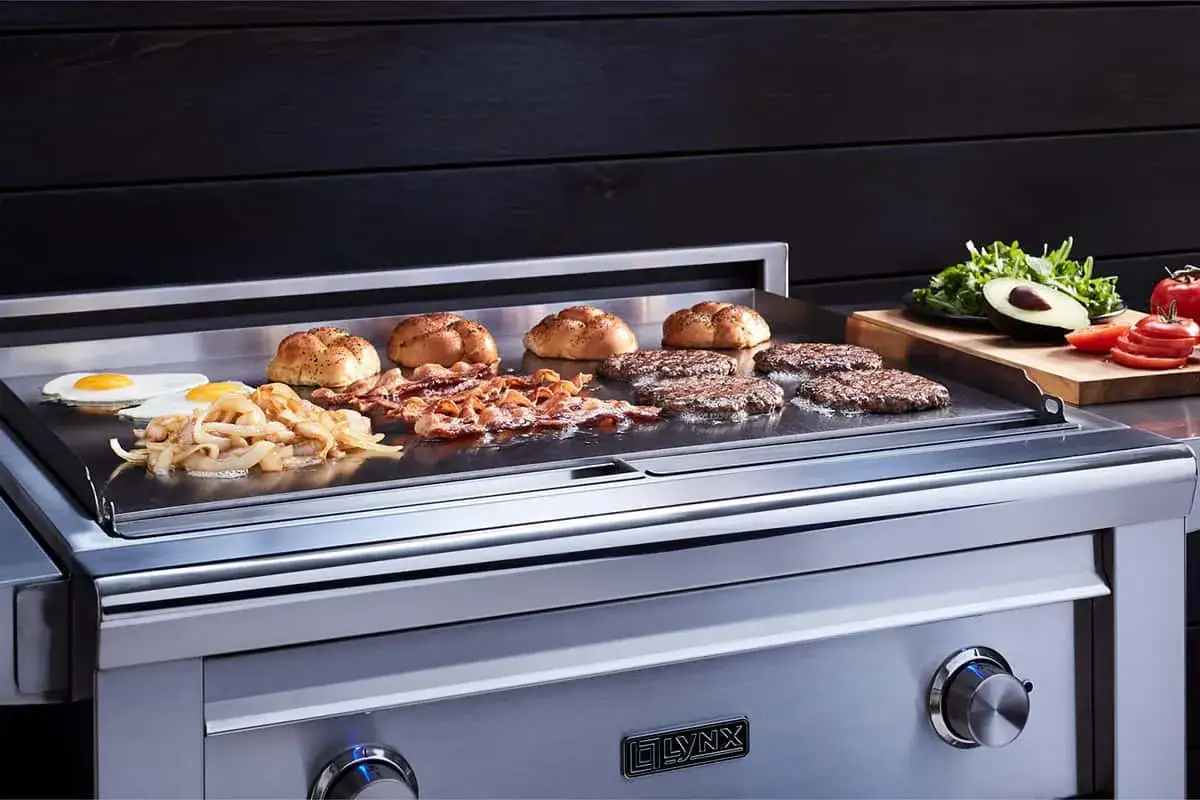 Des hamburgers, bacon, œufs et oignons cuisent sur une plancha gaz. Apprenez comment allumer plancha gaz pour un repas parfait.