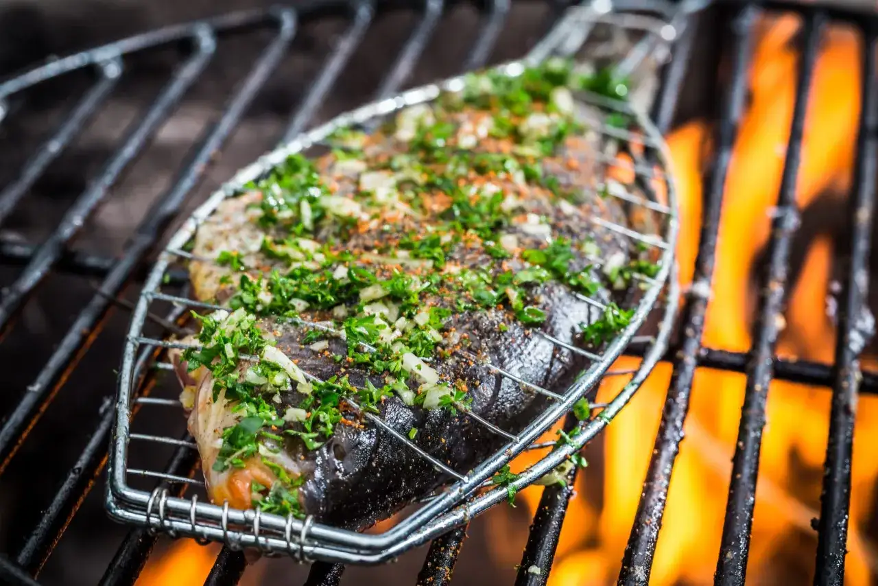 Poisson entier au barbecue, assaisonné d'herbes fraîches et d'épices, grillé sur des flammes vives.
