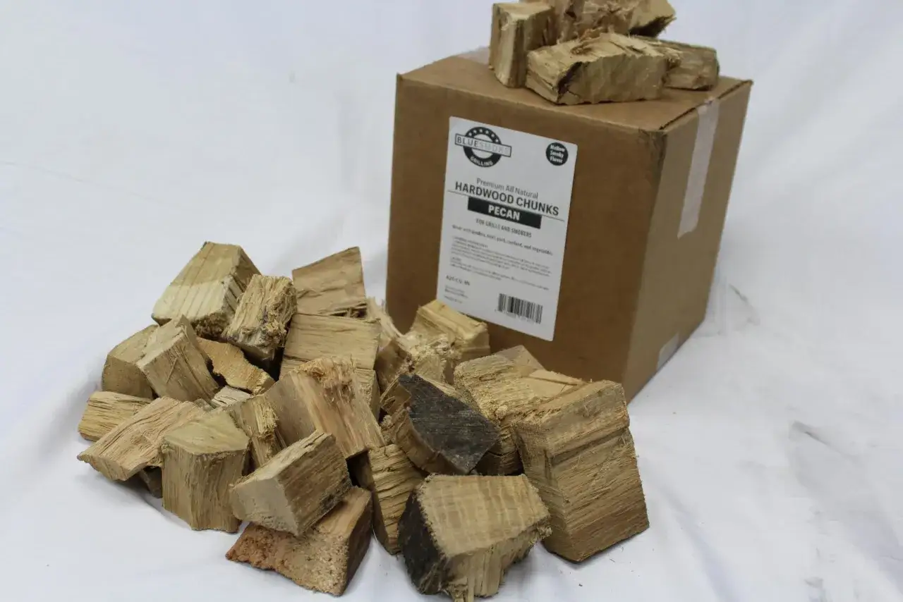 Des morceaux de bois de p&eacute;can pour un d&eacute;licieux fume bleu. Une bo&icirc;te de copeaux de bois est visible &agrave; l'arri&egrave;re.