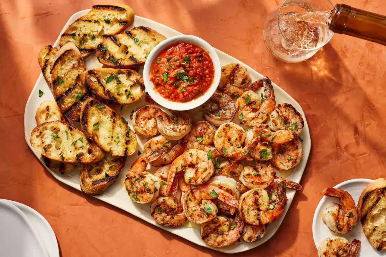 Un plateau généreux d'entrée avec gambas grillées, accompagnées de pain grillé et d'une sauce tomate épicée. Un délice pour les papilles !