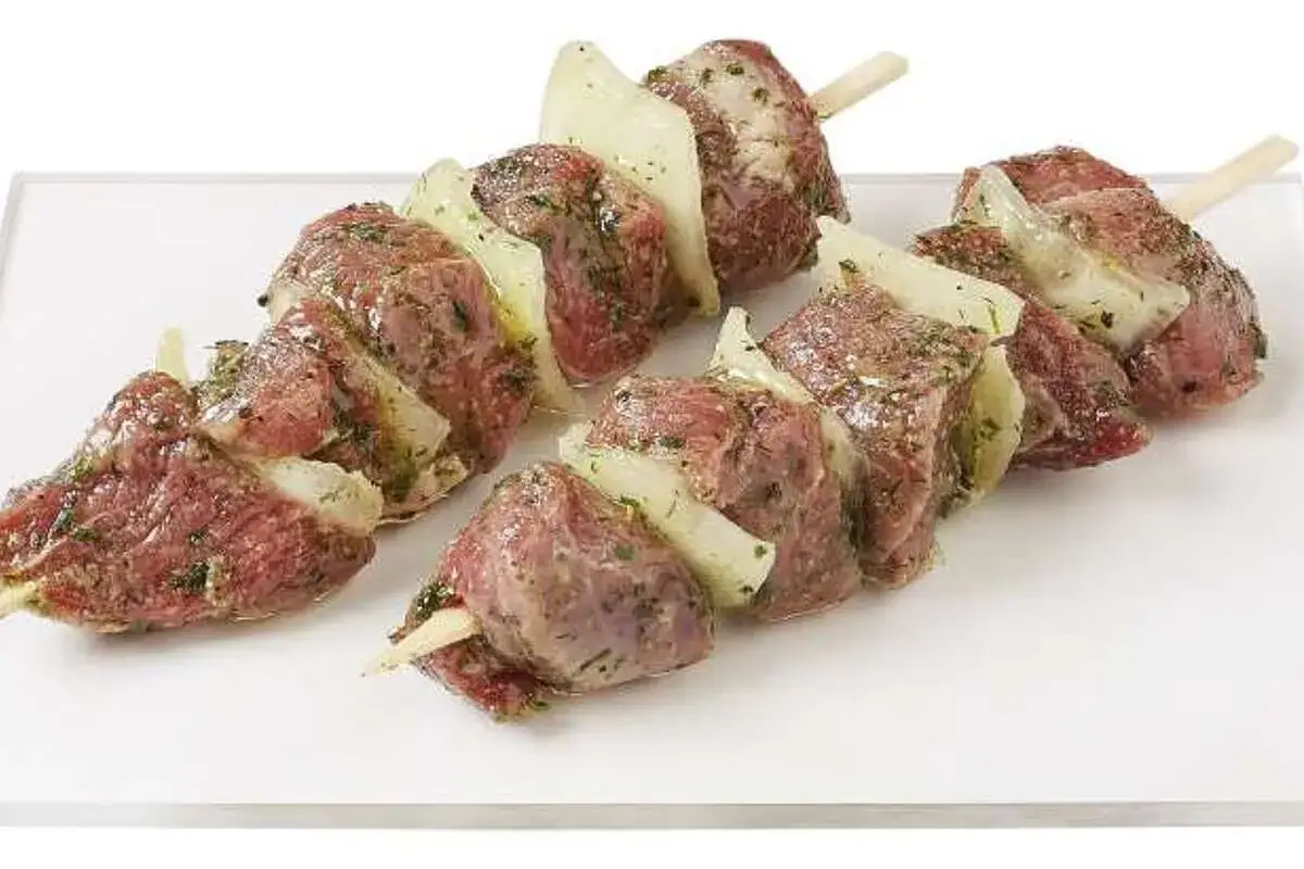 Brochettes d'agneau marinées, prêtes pour la cuisson au barbecue. Les morceaux de viande sont alternés avec des oignons.