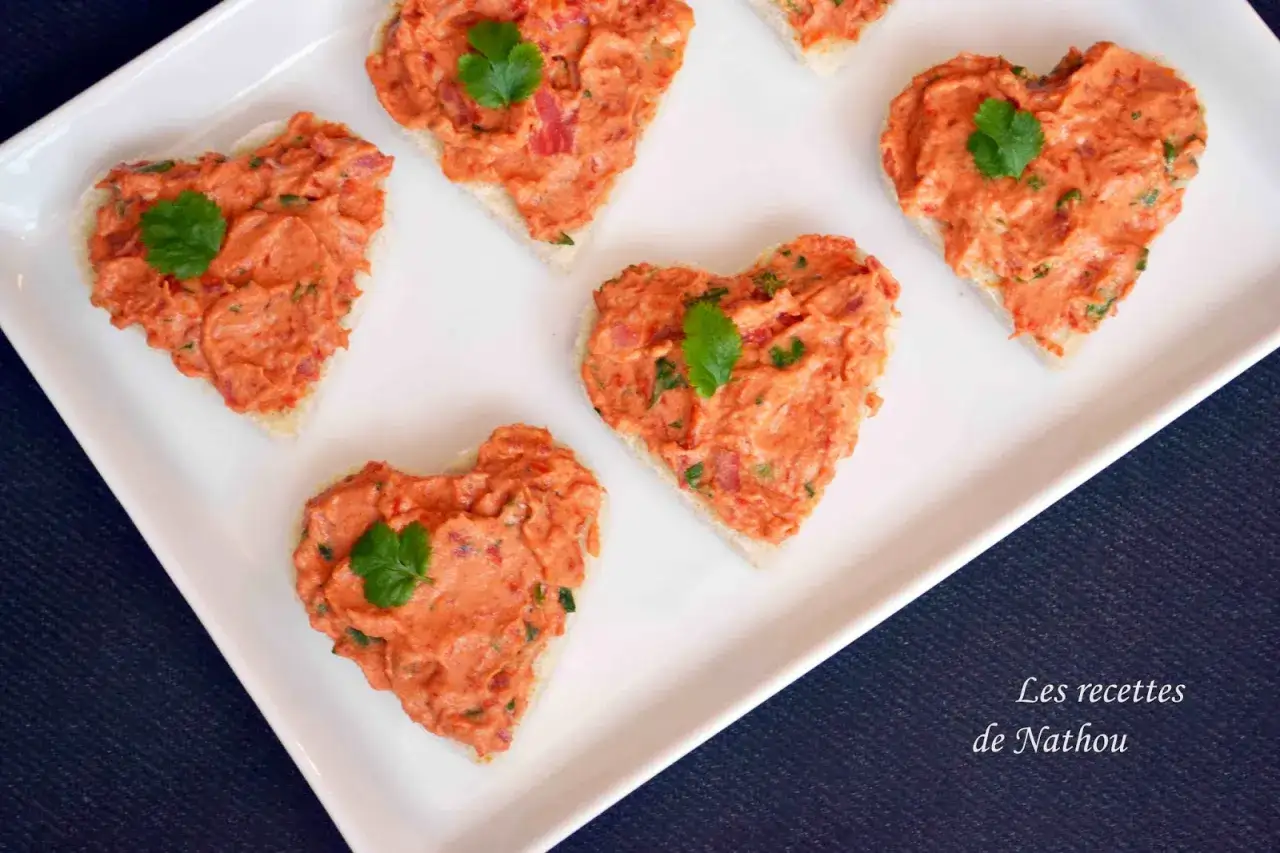 Petits toasts en forme de cœur garnis de rillettes de chorizo, décorés d'une feuille de persil.