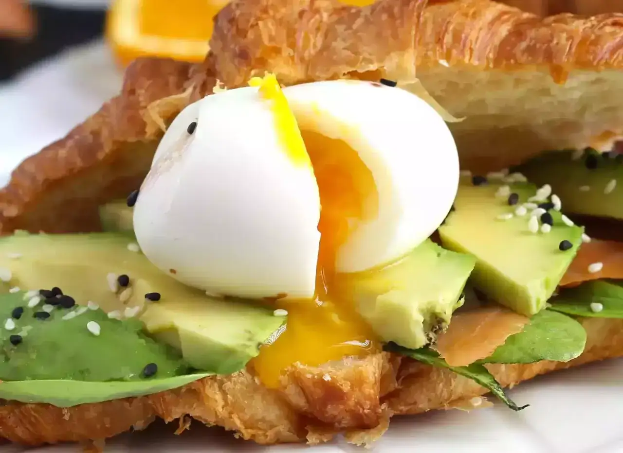 Croissant garni d'avocat, saumon et œuf mollet cuisson parfaite, le jaune coulant.