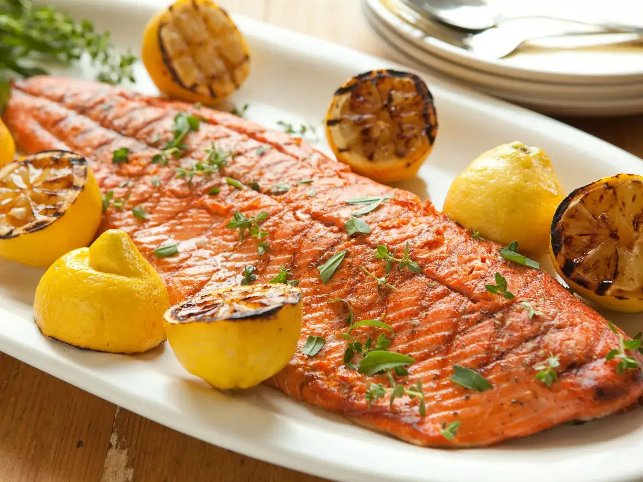 Un magnifique saumon entier au barbecue, garni de citrons grill&eacute;s et de thym frais, pr&ecirc;t &agrave; &ecirc;tre d&eacute;gust&eacute;.