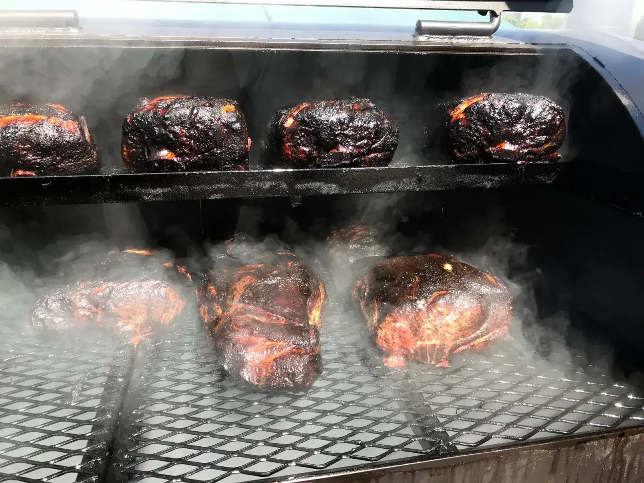 Viande fum&eacute;e dans un fumoir, avec une bouteille de gaz visible &agrave; l'ext&eacute;rieur. La fum&eacute;e s'&eacute;chappe, cr&eacute;ant une atmosph&egrave;re app&eacute;tissante.