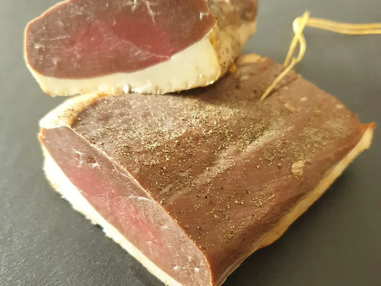 Deux magrets de canard fumés, assaisonnés de poivre, prêts à être dégustés.