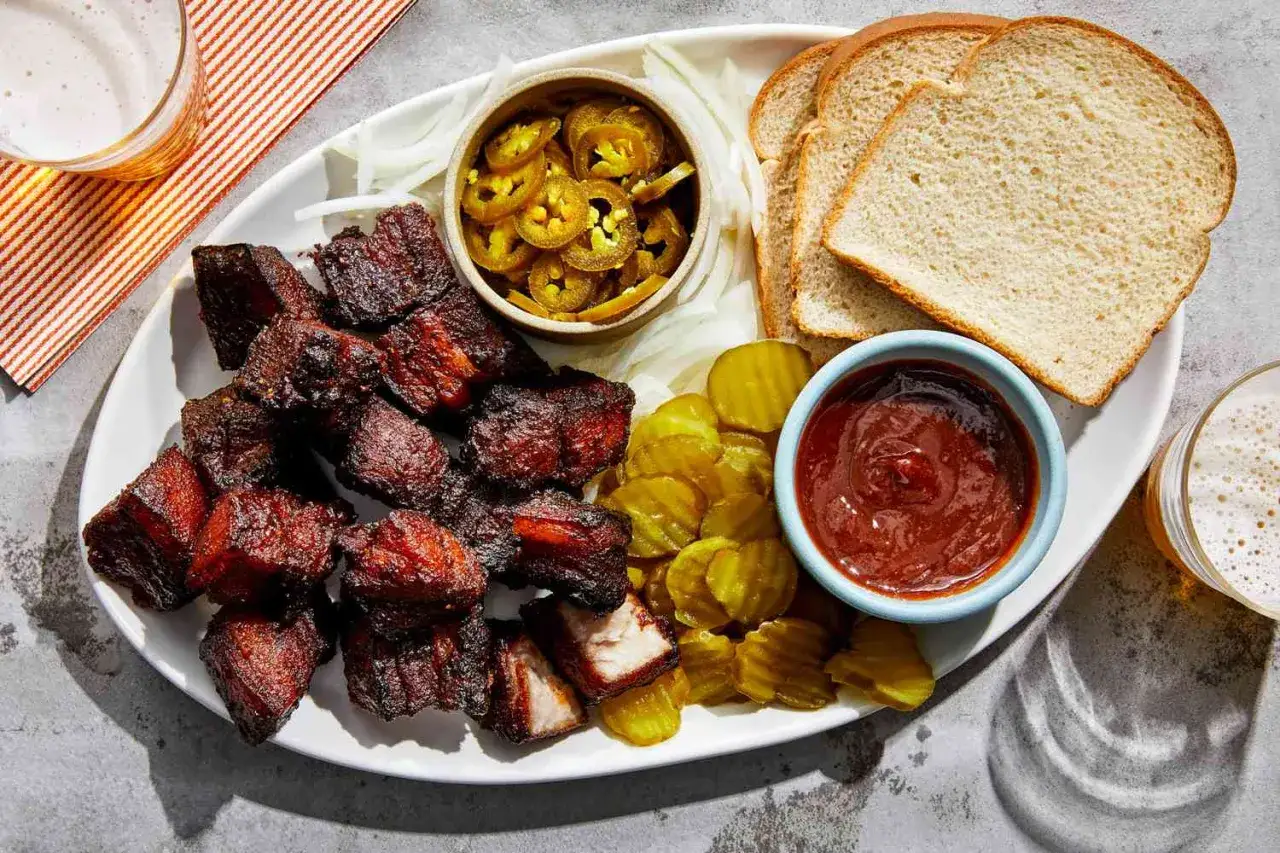 Délicieux morceaux de porc fumé, parfaits pour savoir que faire cuire au barbecue. Accompagnés de pain, cornichons, oignons et jalapeños.