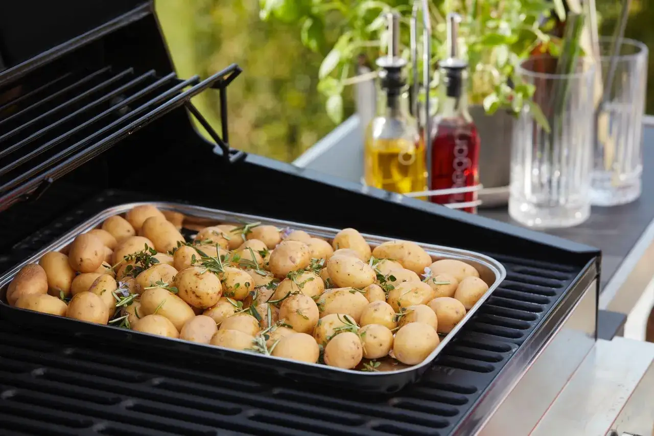 Un plateau de pommes de terre grenaille, assaisonnées d'herbes, est prêt pour le barbecue.